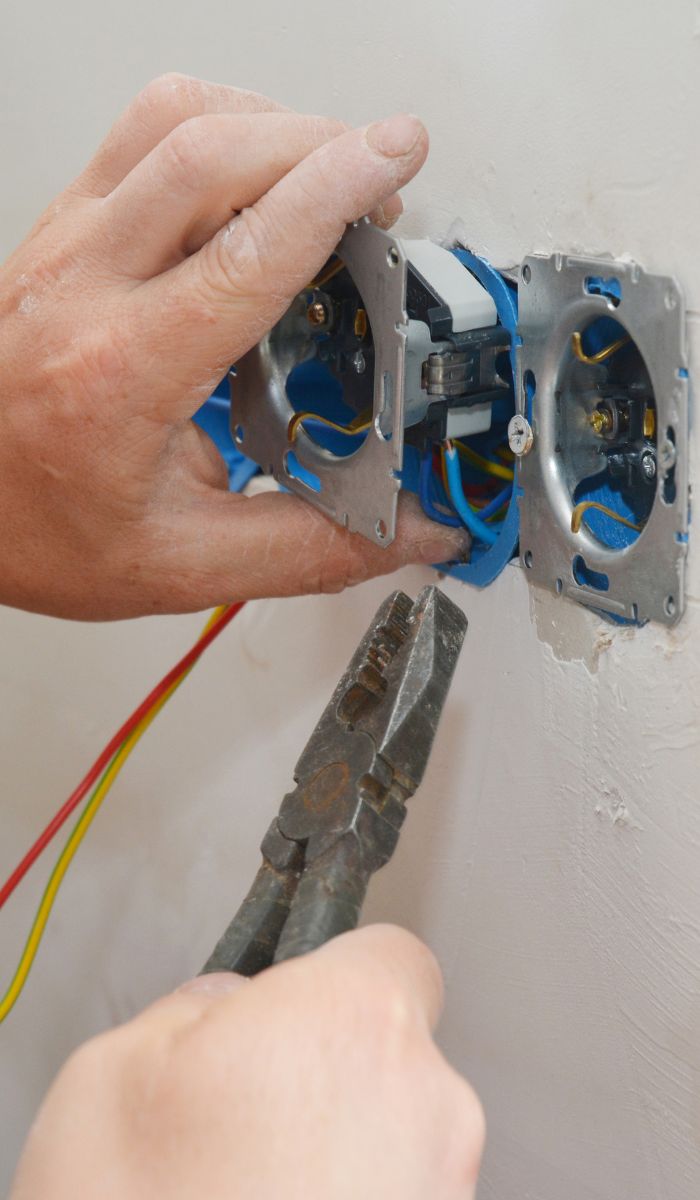 Elektricien sluit bedrading aan in een inbouwdoos in de muur